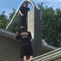 Two men performing a chimney service.