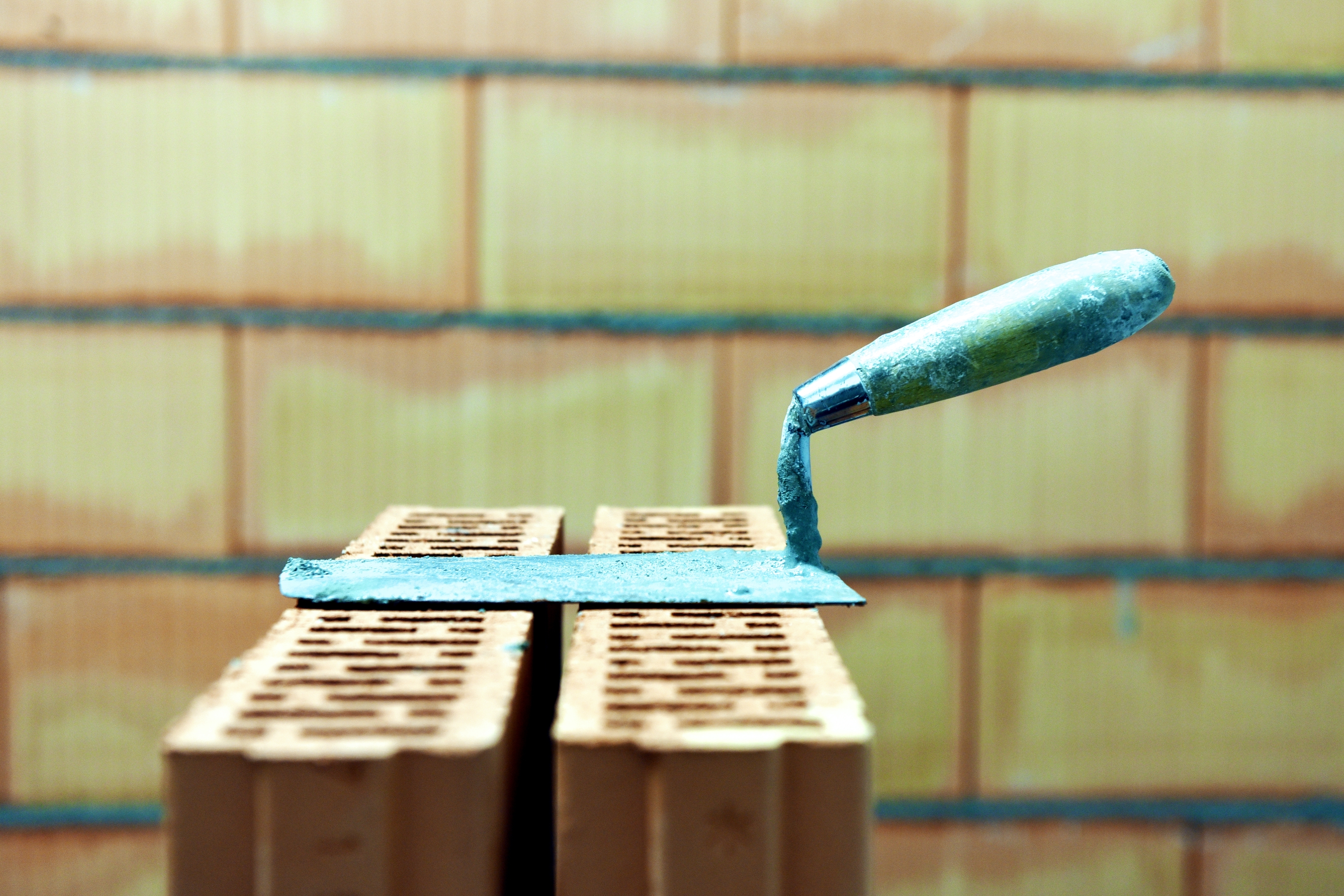 A bricklaying tool placed on top of a stack of bricks.