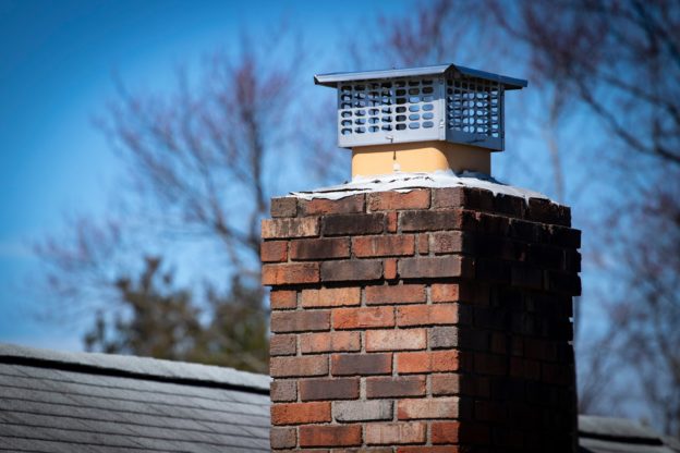 A close-up of a brick chimney on the roof of a house.